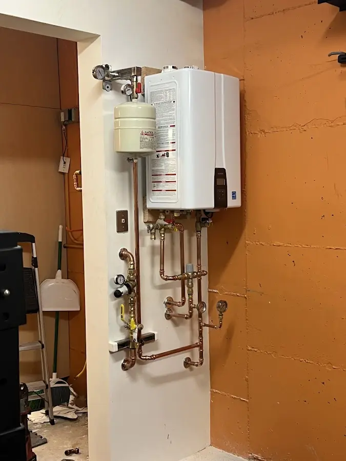 Plumbing technician inspecting water heater connections in La Grande